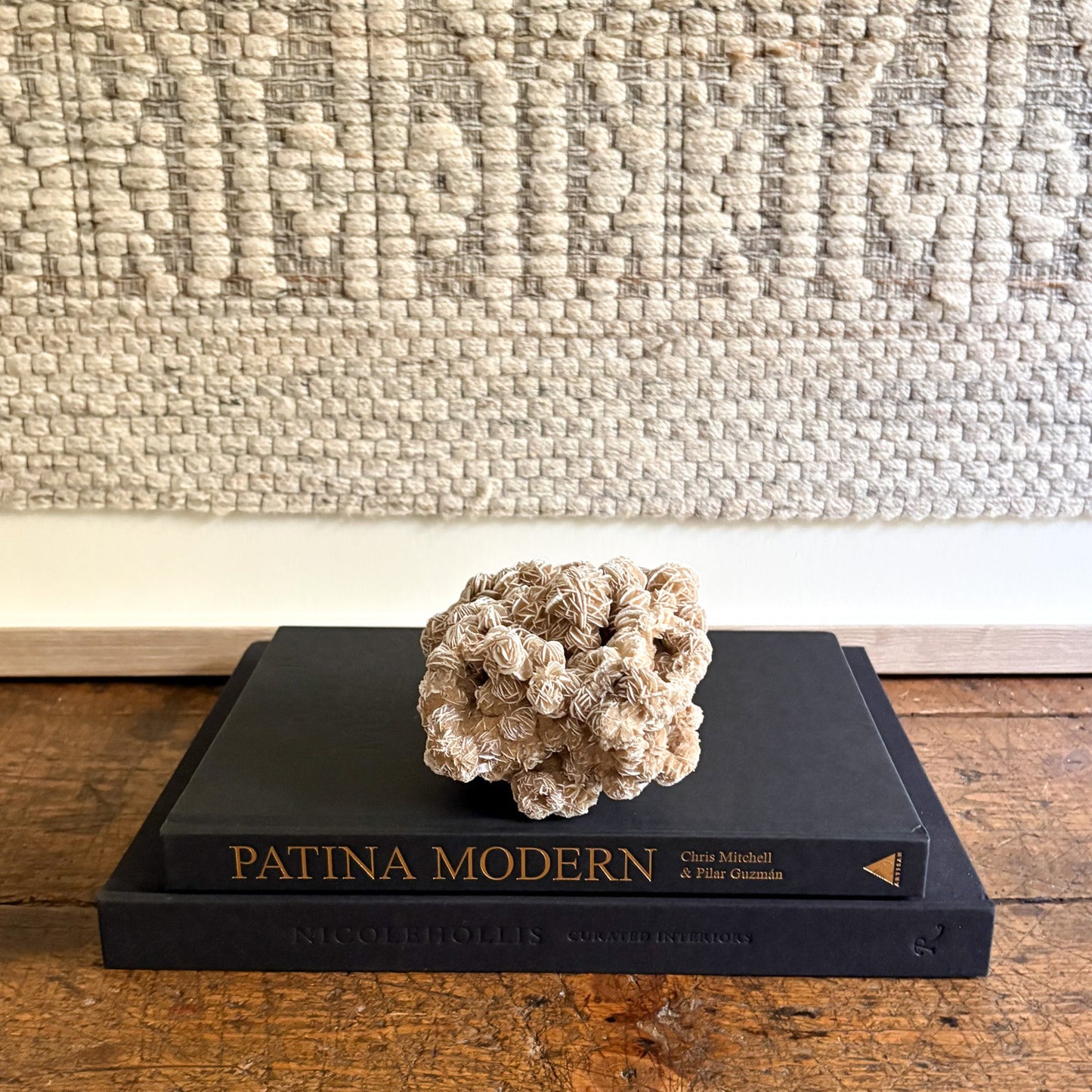 decorative white rose rock on a black book titled 'Patina Modern' against a textured wall.