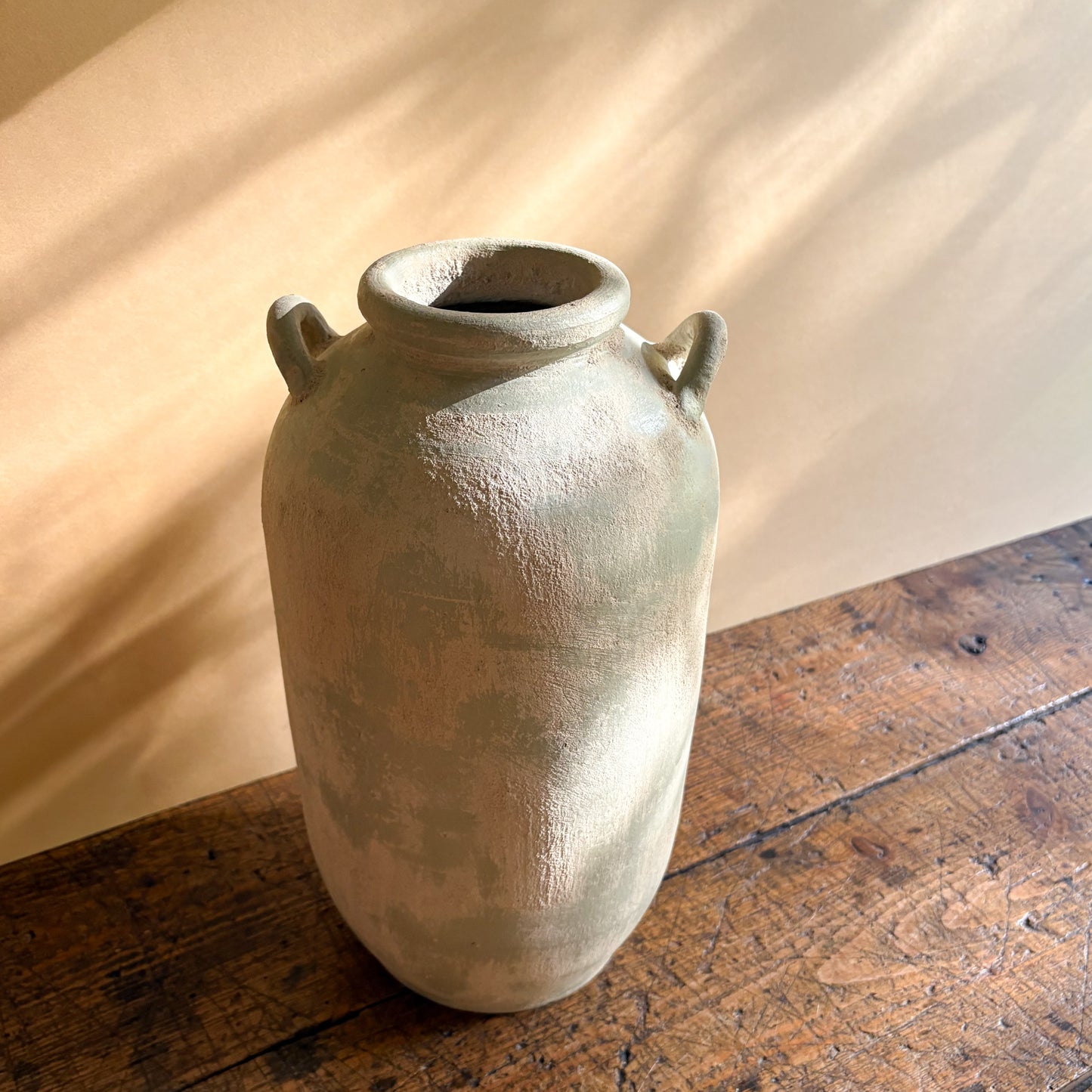 Vintage ceramic vase with handles on a wooden surface