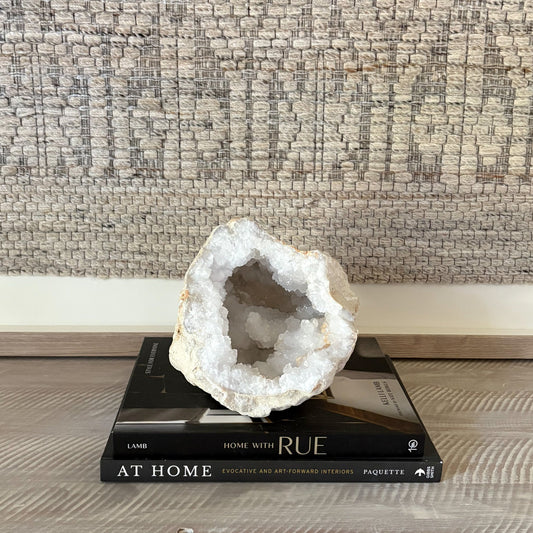 quartz Geode crystal on top of a book titled 'Home with Rue' against a textured wall.