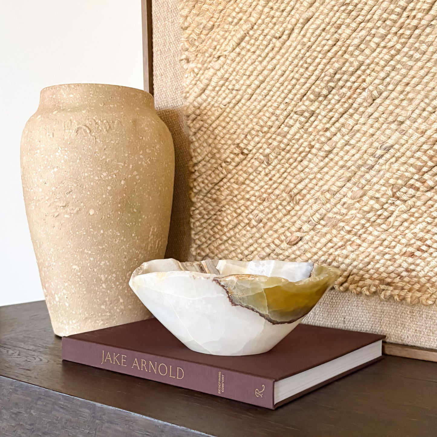 Artisan hand carved olive onyx bowl displayed on a console table