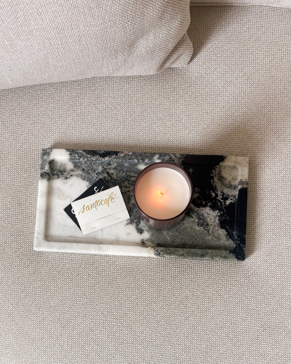 Black and white Panda marble tray styled on a neutral upholstered ottoman