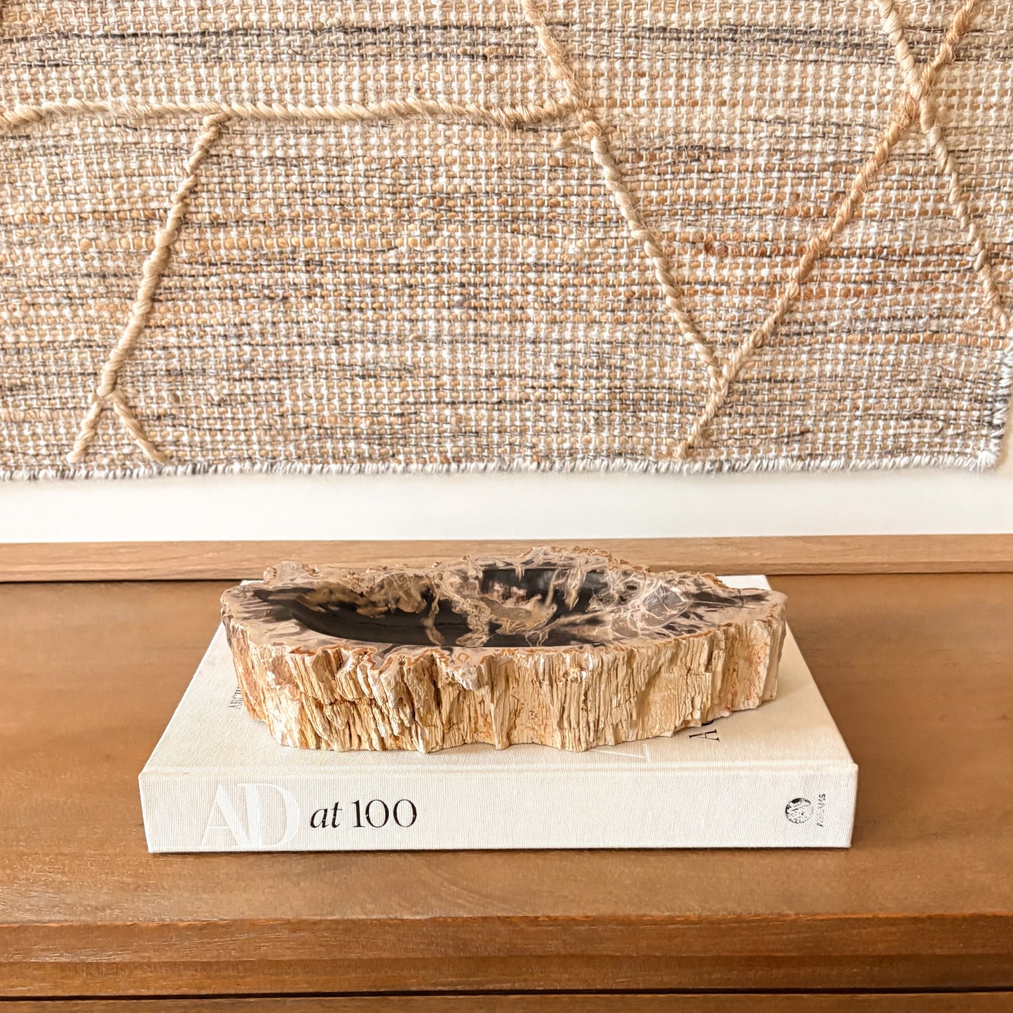Hand-carved Indonesian petrified wood bowl featuring natural crystalized wood patterns and rustic edges, styled as a decorative accent on a wooden table.