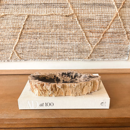 Hand-carved Indonesian petrified wood bowl featuring natural crystalized wood patterns and rustic edges, styled as a decorative accent on a wooden table.