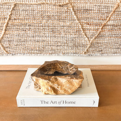 Small Indonesian petrified wood bowl decor resting on a book, natural fossilized wood stone bowl handcrafted from ancient teak wood.