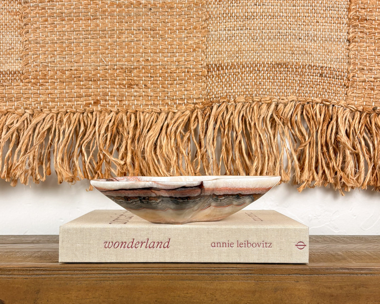 Pink serpentine bowl styled on a coffee table book in a modern organic interior