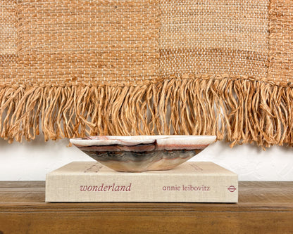 Pink serpentine bowl styled on a coffee table book in a modern organic interior