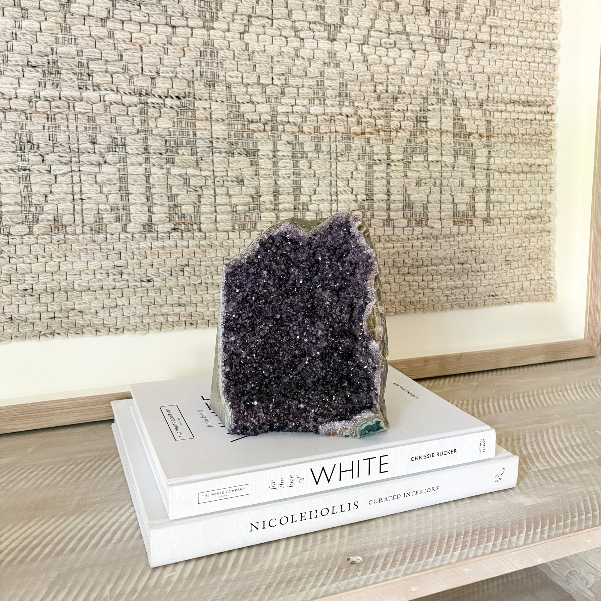 Amethyst crystal on top of books with a textured wall in the background