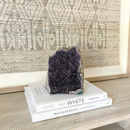 Amethyst crystal on top of books with a textured wall in the background