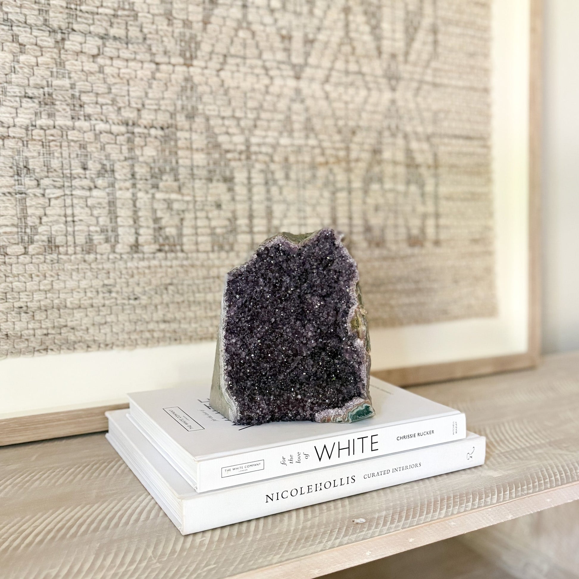 Amethyst crystal on top of books with a textured wall in the background