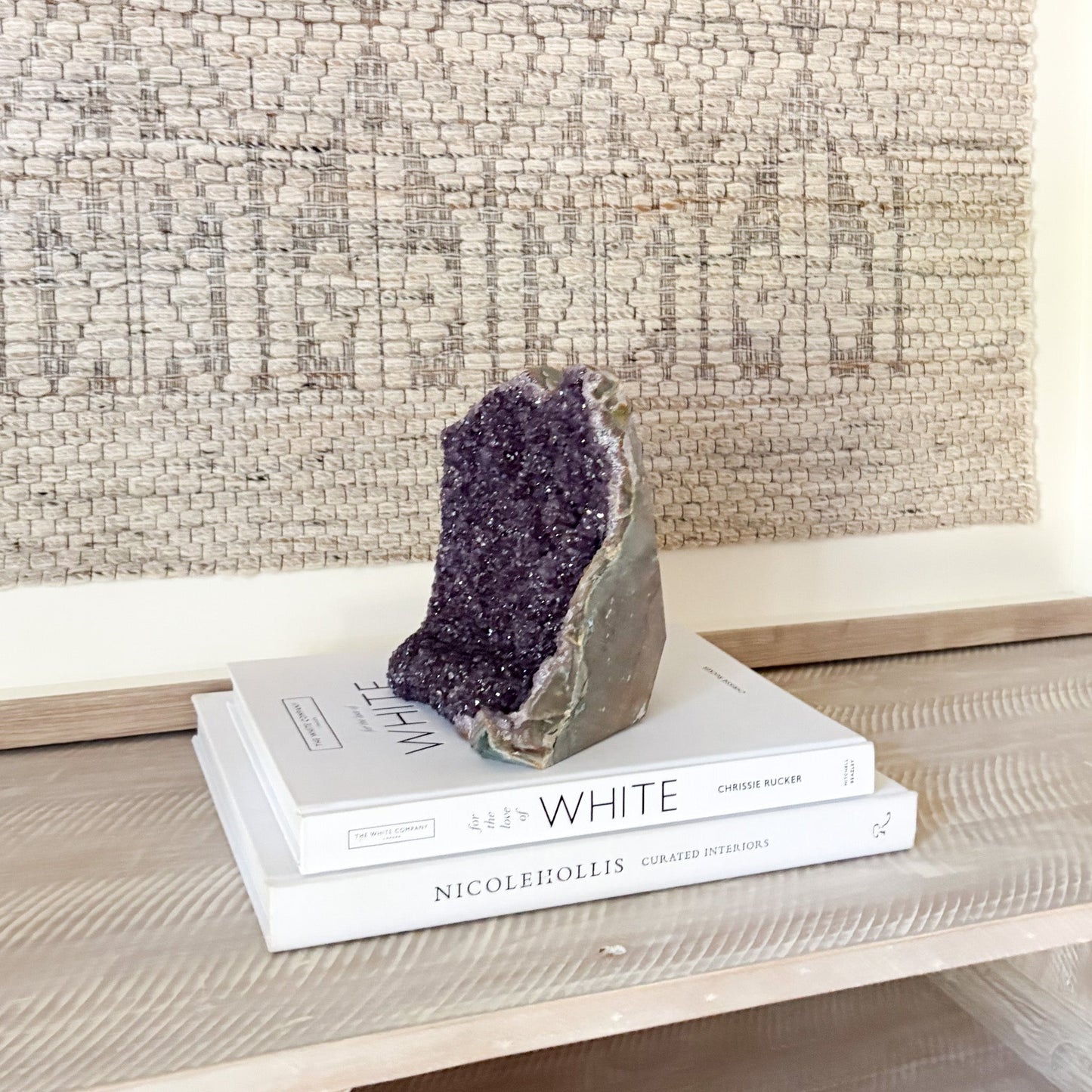 Amethyst crystal on top of books with a textured wall in the background