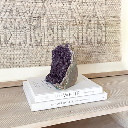 Amethyst crystal on top of books with a textured wall in the background
