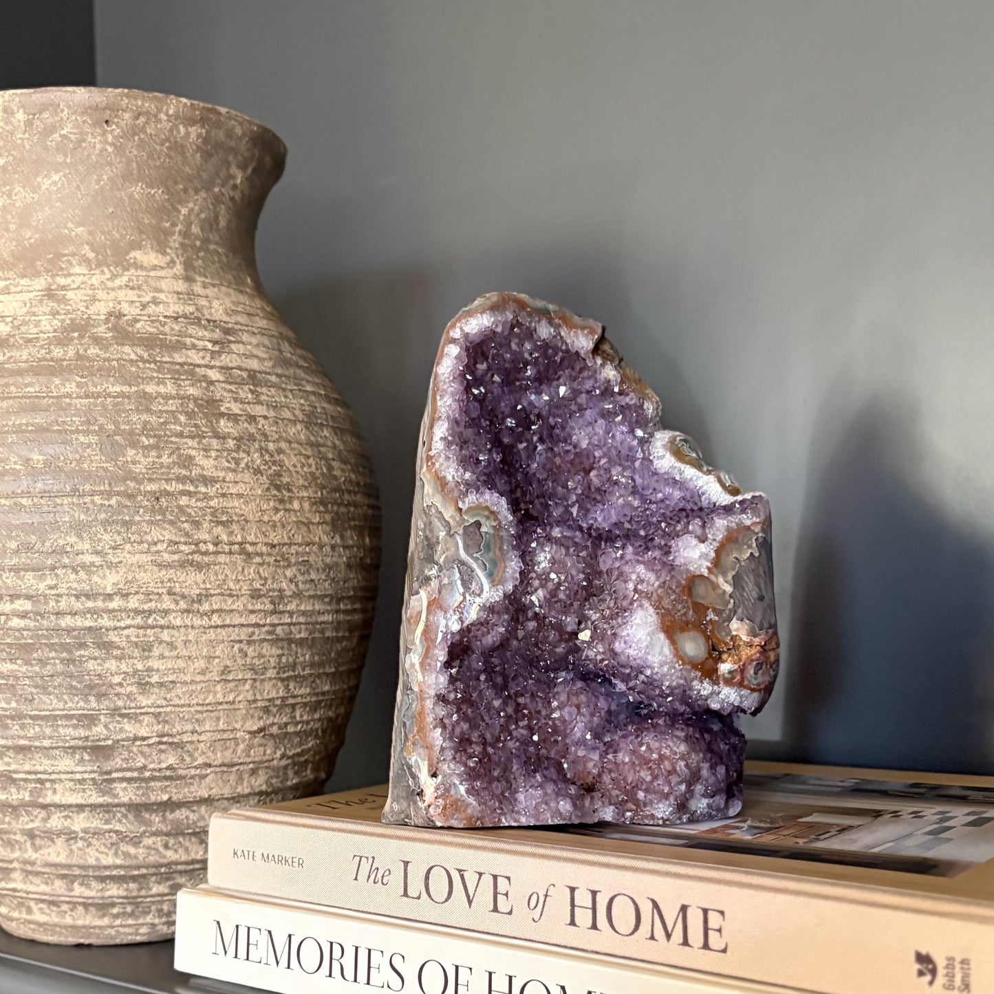 natural purple Amethyst geode on top of books with a textured vase in the background