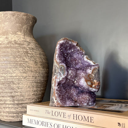 natural purple Amethyst geode on top of books with a textured vase in the background