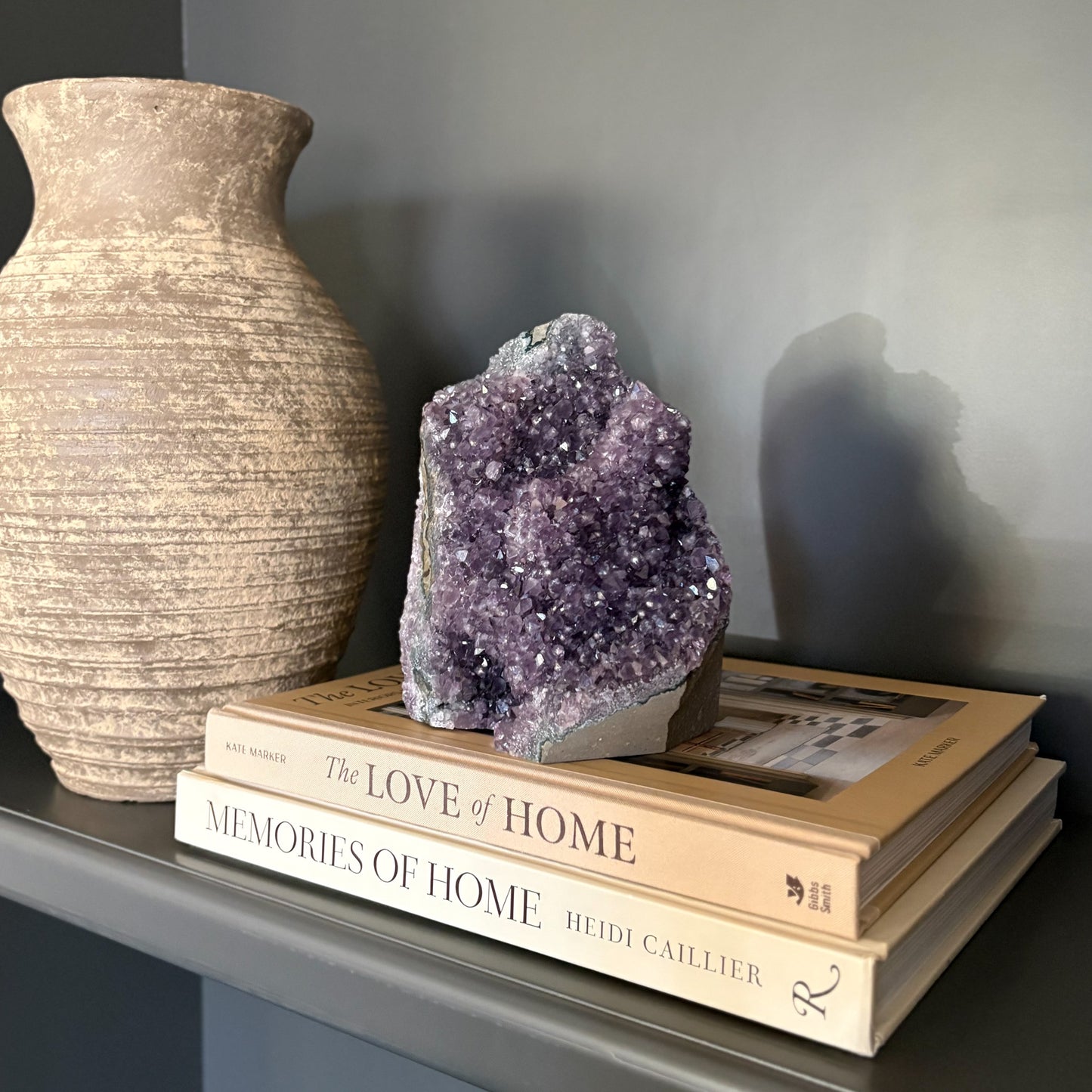 Decorative amethyst crystal stacked on books against a dark background