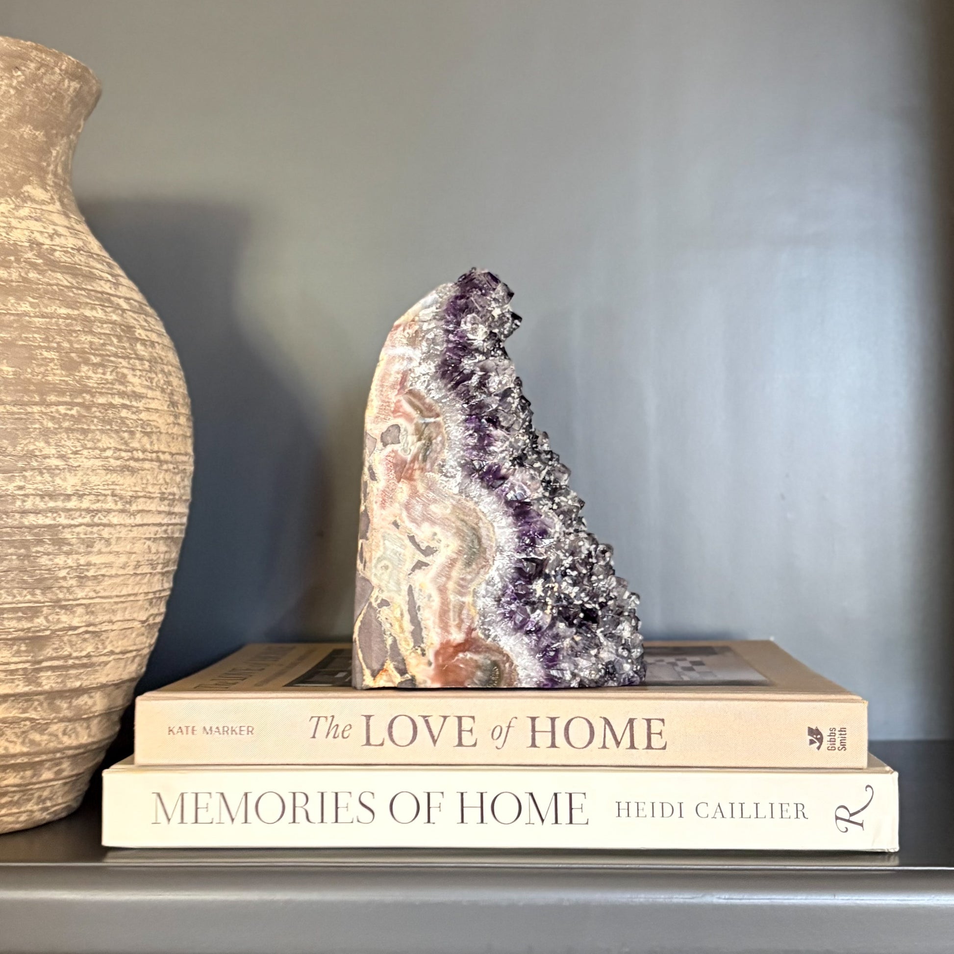 Amethyst crystal with polished edge on top of books with a vase in the background