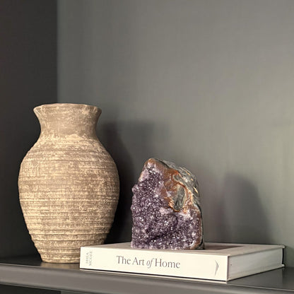 Decorative amethyst geode on modern shelf with neutral pottery and interior styling
