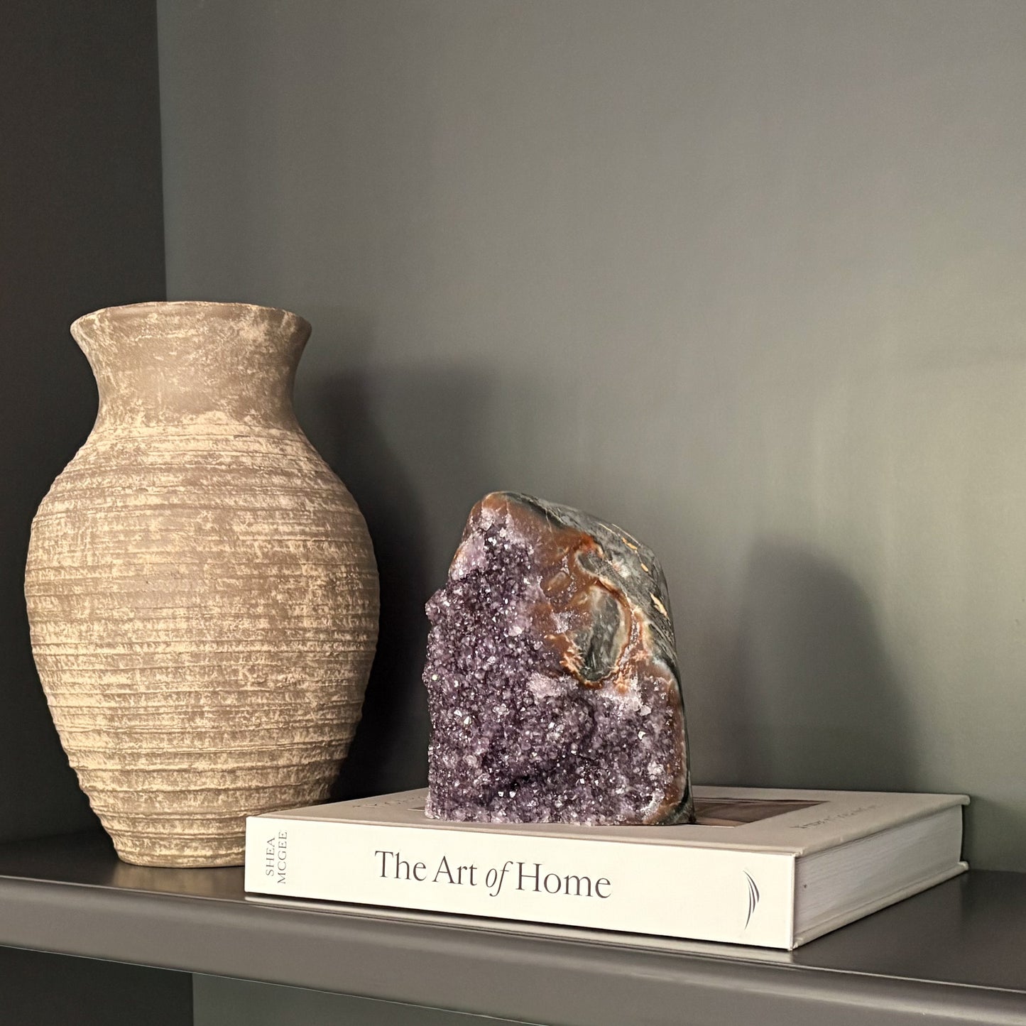 Natural amethyst geode crystal on shelf with neutral vase and book modern home décor