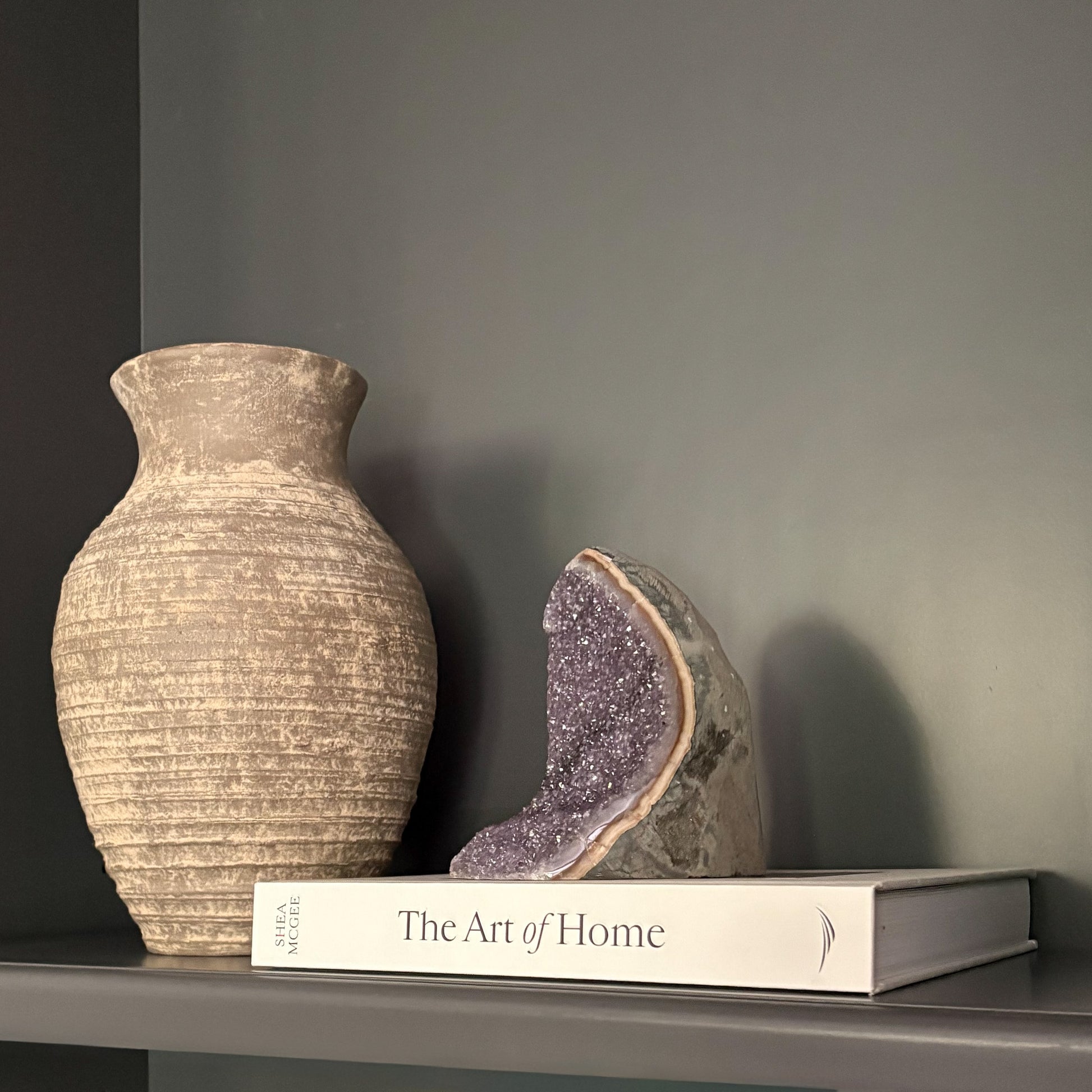 Natural amethyst geode crystal on shelf with neutral vase and book modern home décor