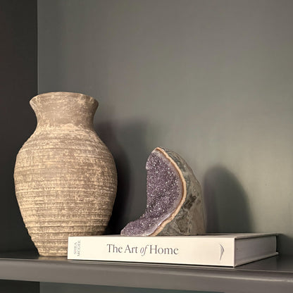 Natural amethyst geode crystal on shelf with neutral vase and book modern home décor