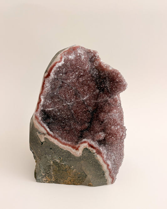 Natural amethyst geode with sparkling mauve-purple crystals and rough stone exterior