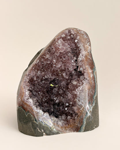 Natural amethyst geode with sparkling mauve-purple crystals and rough stone exterior