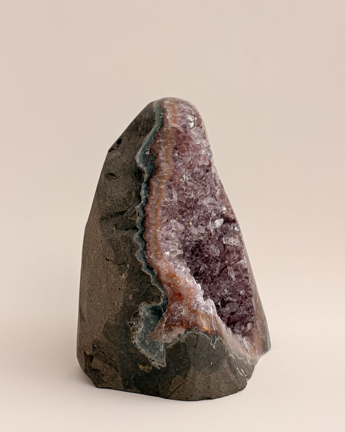 Large amethyst geode with textured purple crystals and natural stone base