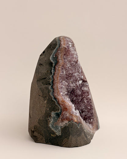 Large amethyst geode with textured purple crystals and natural stone base
