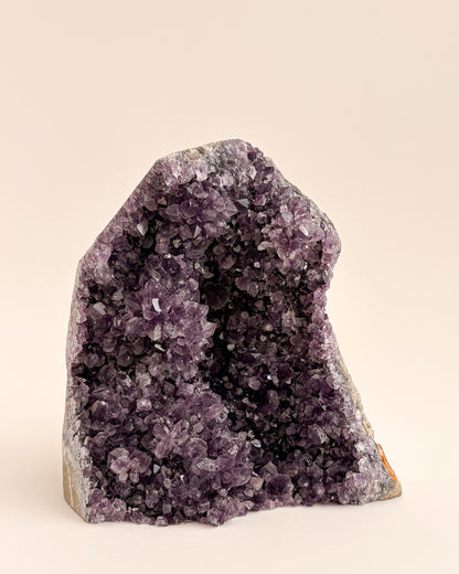 Natural amethyst geode with sparkling mauve-purple crystals and rough stone exterior