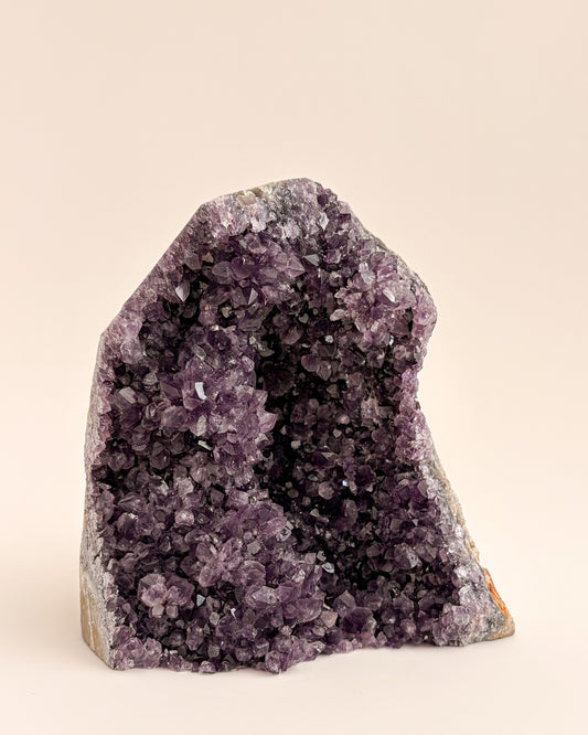 Natural amethyst geode with sparkling mauve-purple crystals and rough stone exterior