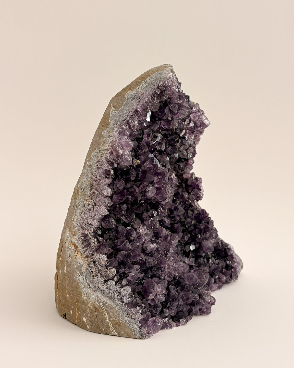 Large amethyst geode with textured purple crystals and natural stone base