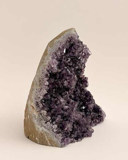 Large amethyst geode with textured purple crystals and natural stone base