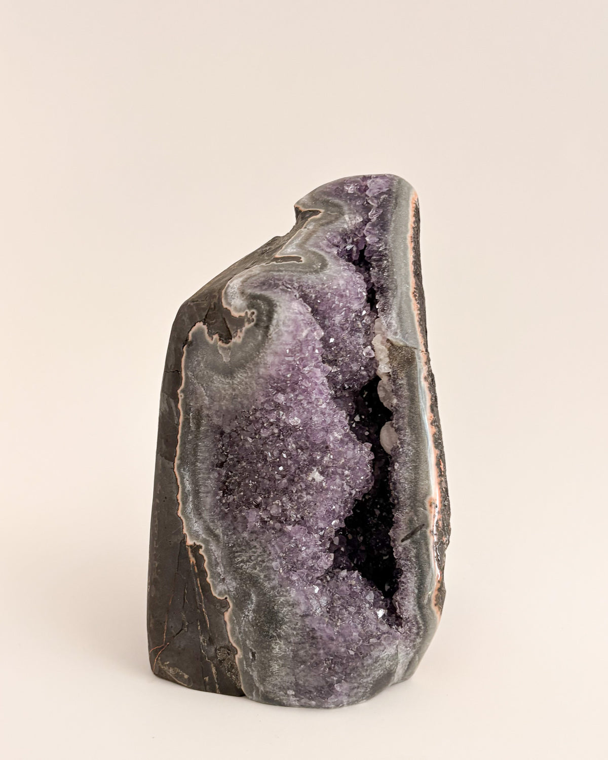 Natural amethyst geode with sparkling mauve-purple crystals and rough stone exterior