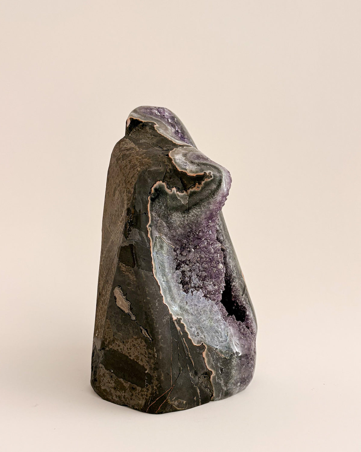 Large amethyst geode with textured purple crystals and natural stone base