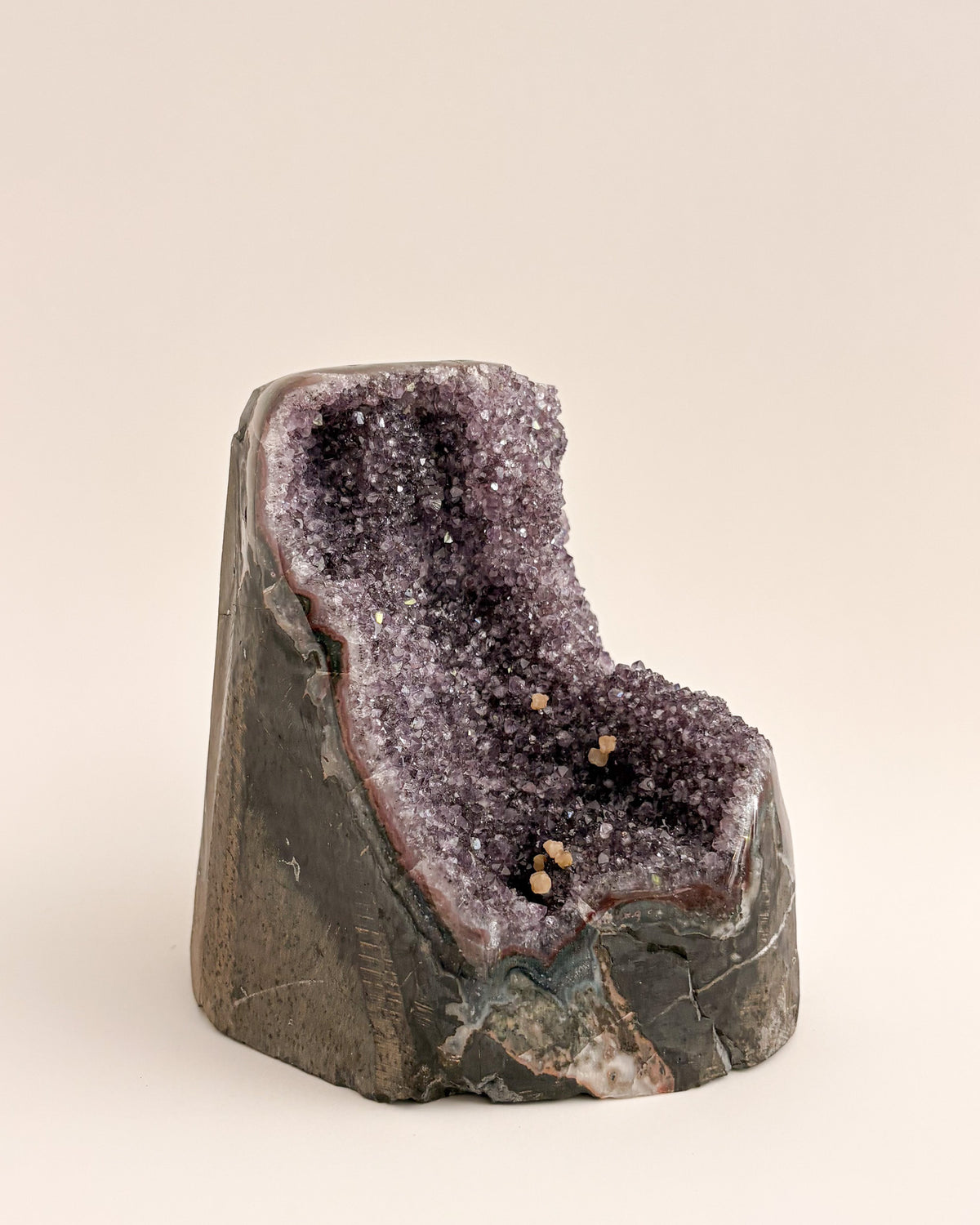 Large amethyst geode with textured purple crystals and natural stone base