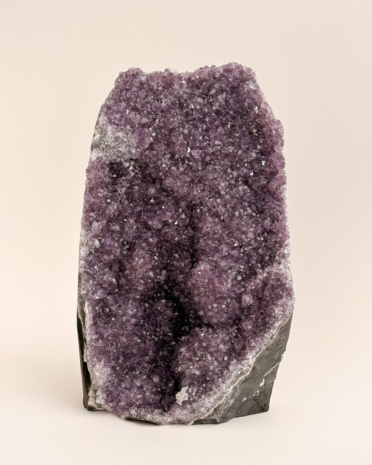 Natural amethyst geode with sparkling mauve-purple crystals and rough stone exterior