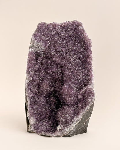 Natural amethyst geode with sparkling mauve-purple crystals and rough stone exterior