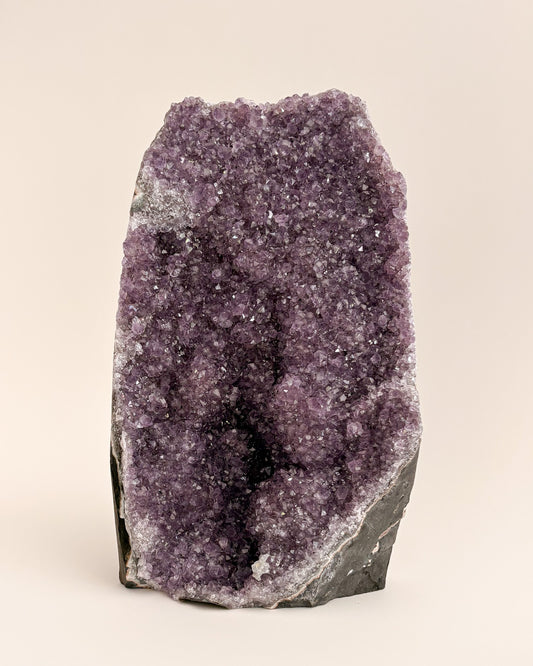 Natural amethyst geode with sparkling mauve-purple crystals and rough stone exterior