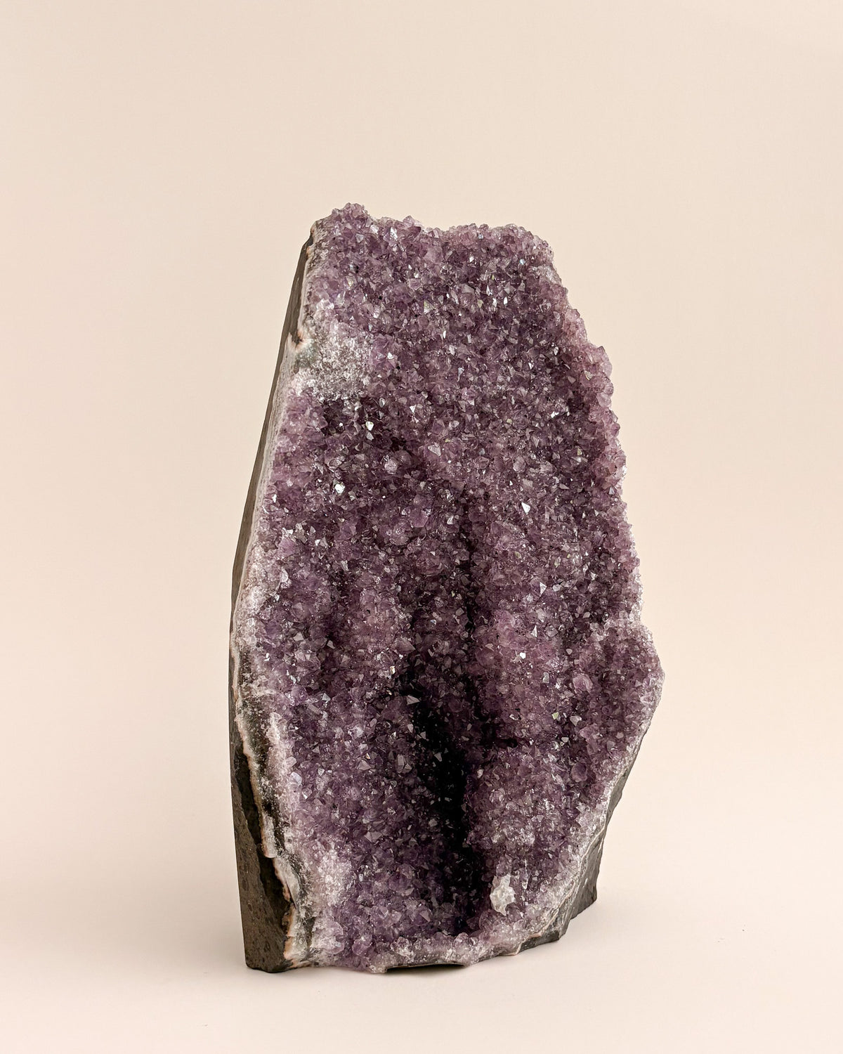 Large amethyst geode with textured purple crystals and natural stone base