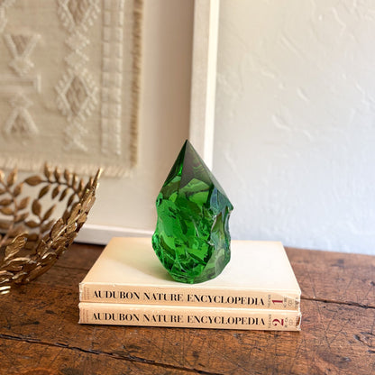 Green glass sculpture on top of two 'Audubon Nature Encyclopedia' books with a decorative wall in the background.