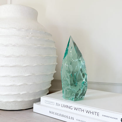 Green crystal sculpture on books with a white vase in the background