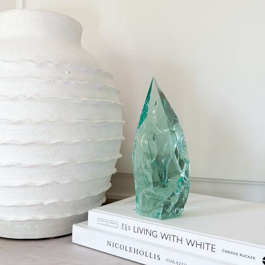Green crystal sculpture on books with a white vase in the background
