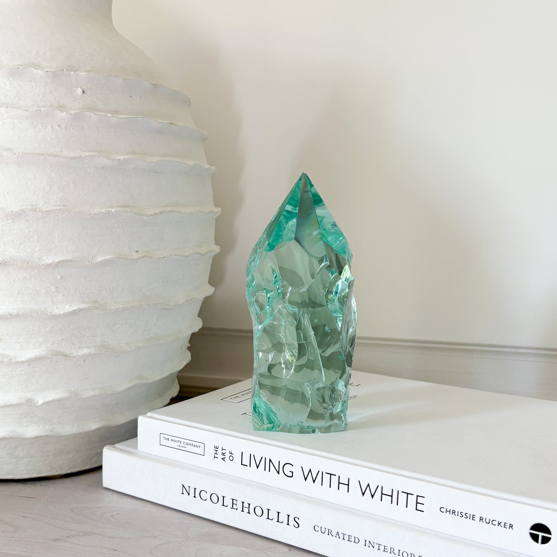 Turquoise crystal on a stack of books with a white textured vase in the background