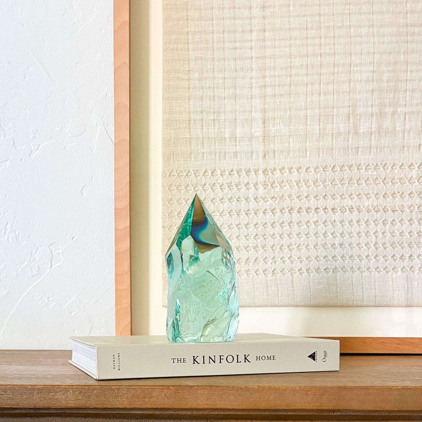 Minimalist home decor with aqua glass sculpture on wooden surface