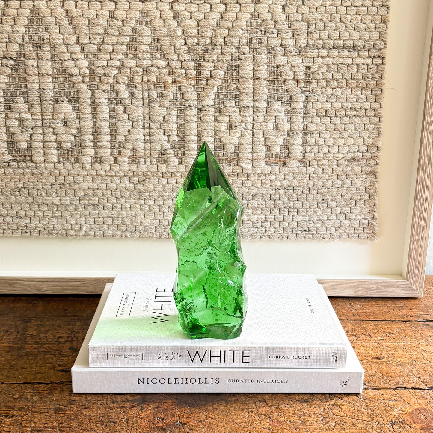 Hand-cut emerald green glass crystal point styled as a modern decorative accent on design books