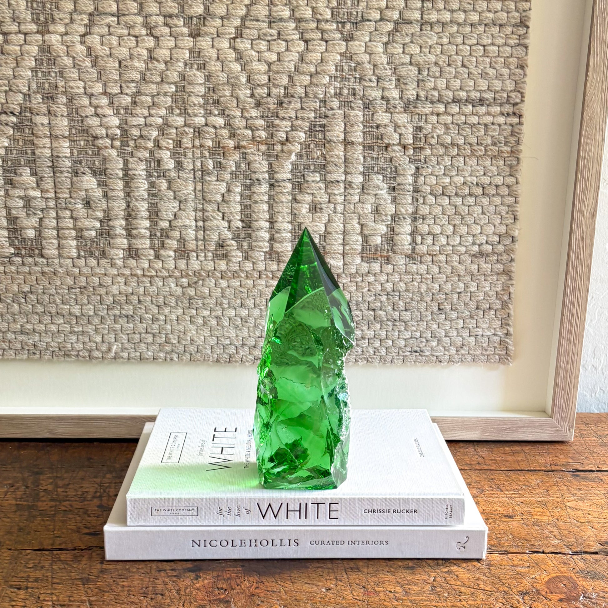 Rustic green glass crystal point decor accent styled on stacked books against textured wall