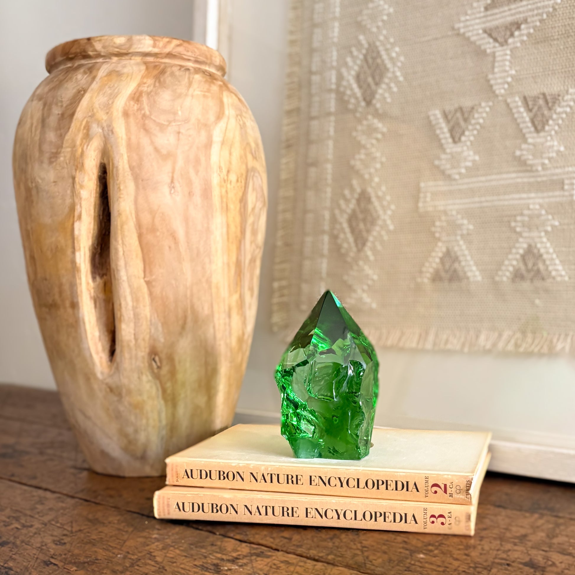 Green glass crystal point decor on stacked books beside carved wood vase