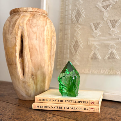 Green glass crystal point decor on stacked books beside carved wood vase