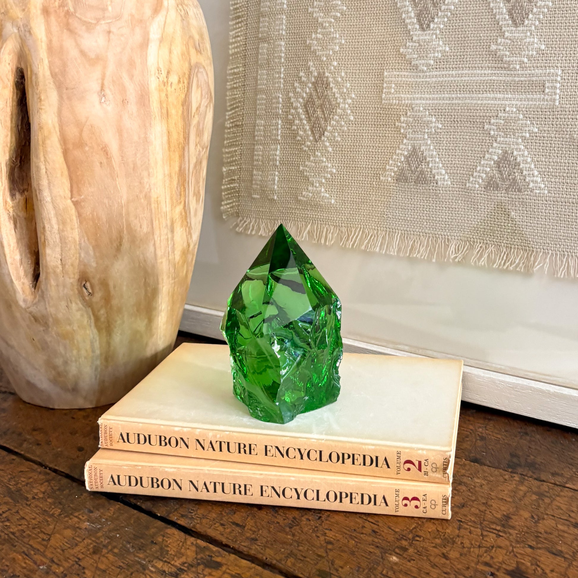 Rustic green glass obelisk point styled on books in boho neutral decor setting
