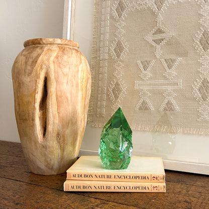 Green glass crystal point decor on stacked books beside carved wood vase