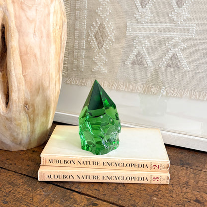 Green glass crystal point decor on stacked books beside carved wood vase